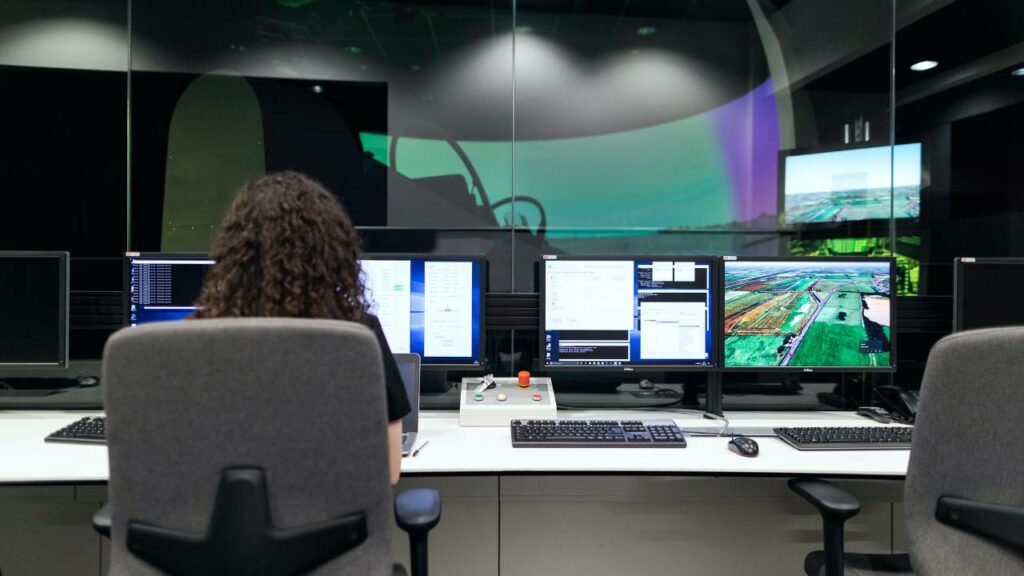 Female employee sitting in front of multiple computer screens